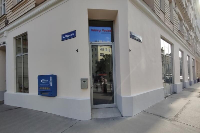 Außenansicht unseres Geschäftslokal am Ilgplatz 2 in 1020, Eckeingang in einem Altbau mit beiger Fassade und grauem Sockel, links an der Wand hängt ein Schwalbe Schlauchautomat